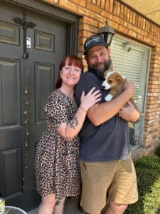 A man and a woman with their Corgi puppy